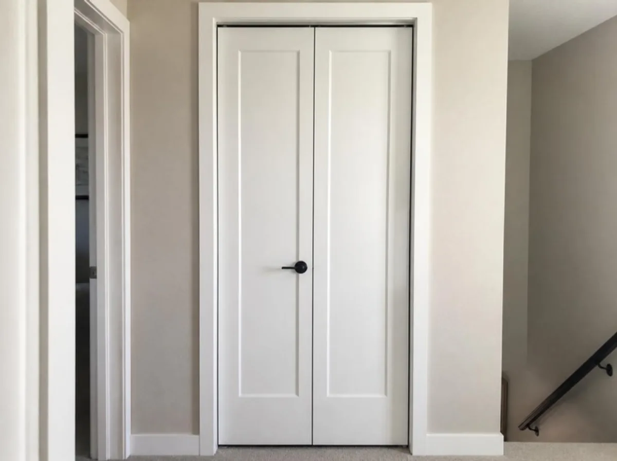 Modern white bifold closet doors with clean hardware in a bright hallway